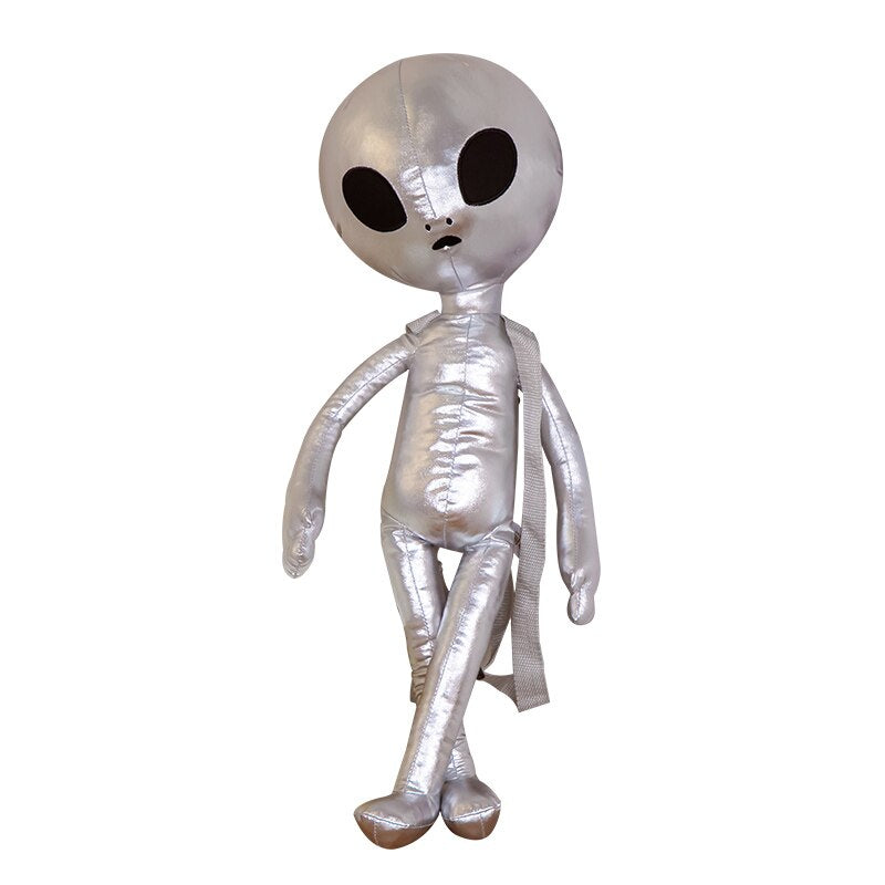 Sac à dos peluche alien posé sur une surface en bois clair