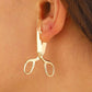 Boucles d'oreilles ciseaux en métal sur fond blanc