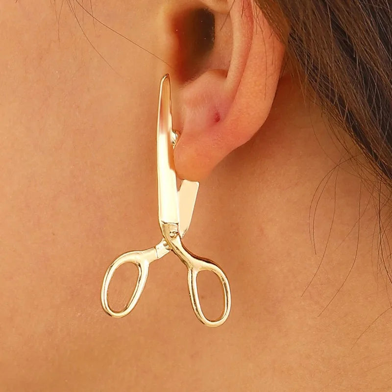 Boucles d'oreilles ciseaux en métal sur fond blanc