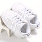 Chaussures bébé présentées avec un jouet en arrière-plan
