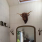 Sculpture de vache accrochée sur un mur clair