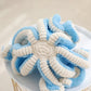 Peluche octopus douce posée sur un lit blanc