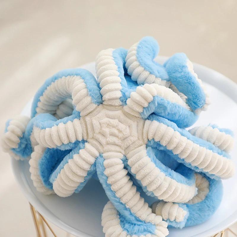 Peluche octopus douce posée sur un lit blanc