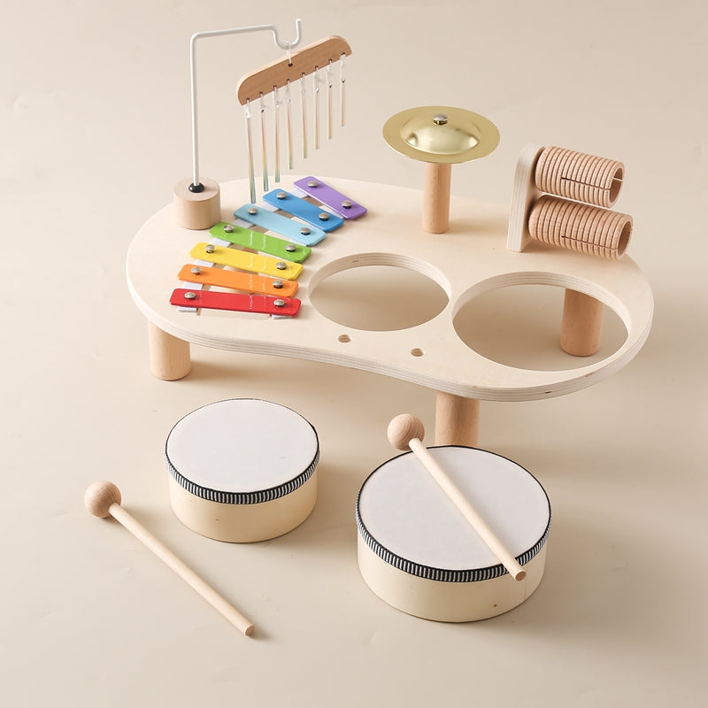 Enfant jouant sur une table musicale en bois avec divers instruments