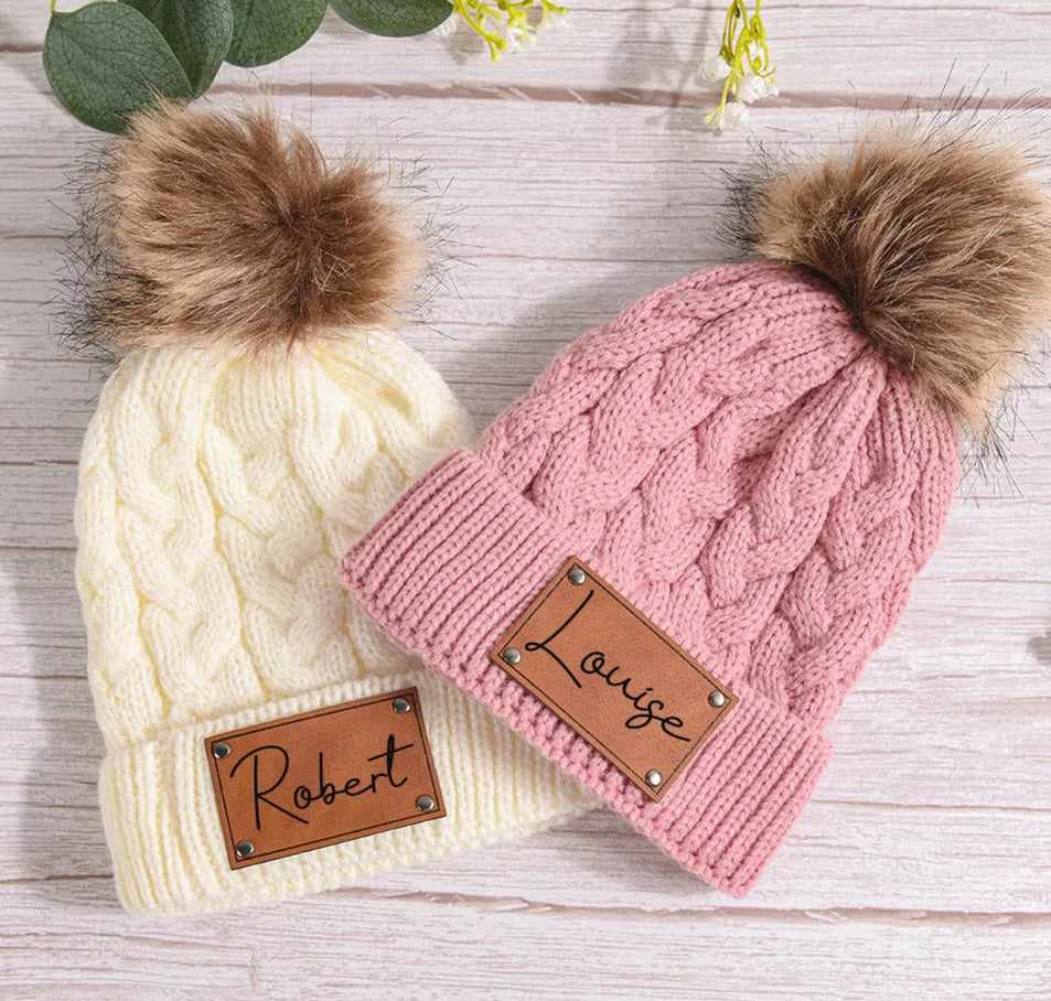 Bonnet avec pompon, couleur neutre, posé sur table