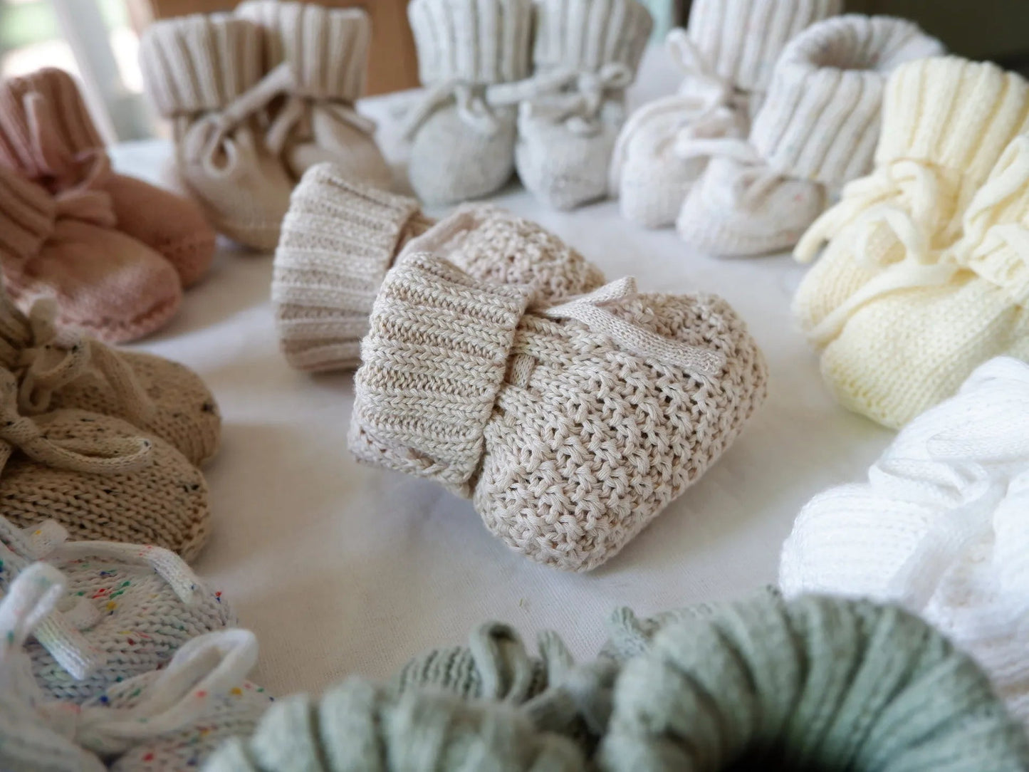 Chaussons bébé en tricot gris posés sur une couverture