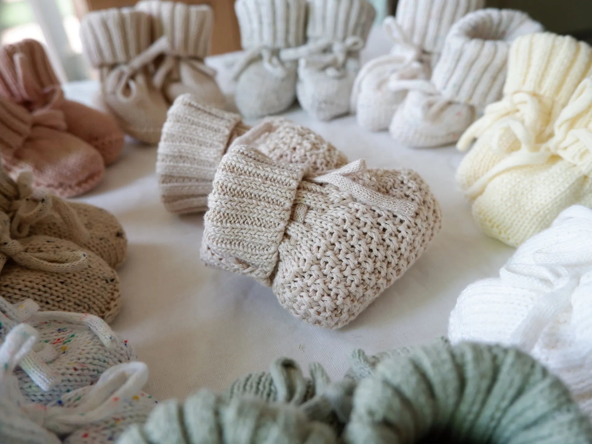 Chaussons bébé en tricot gris posés sur une couverture