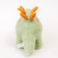 Dinosaure en peluche vert posé sur un fond neutre