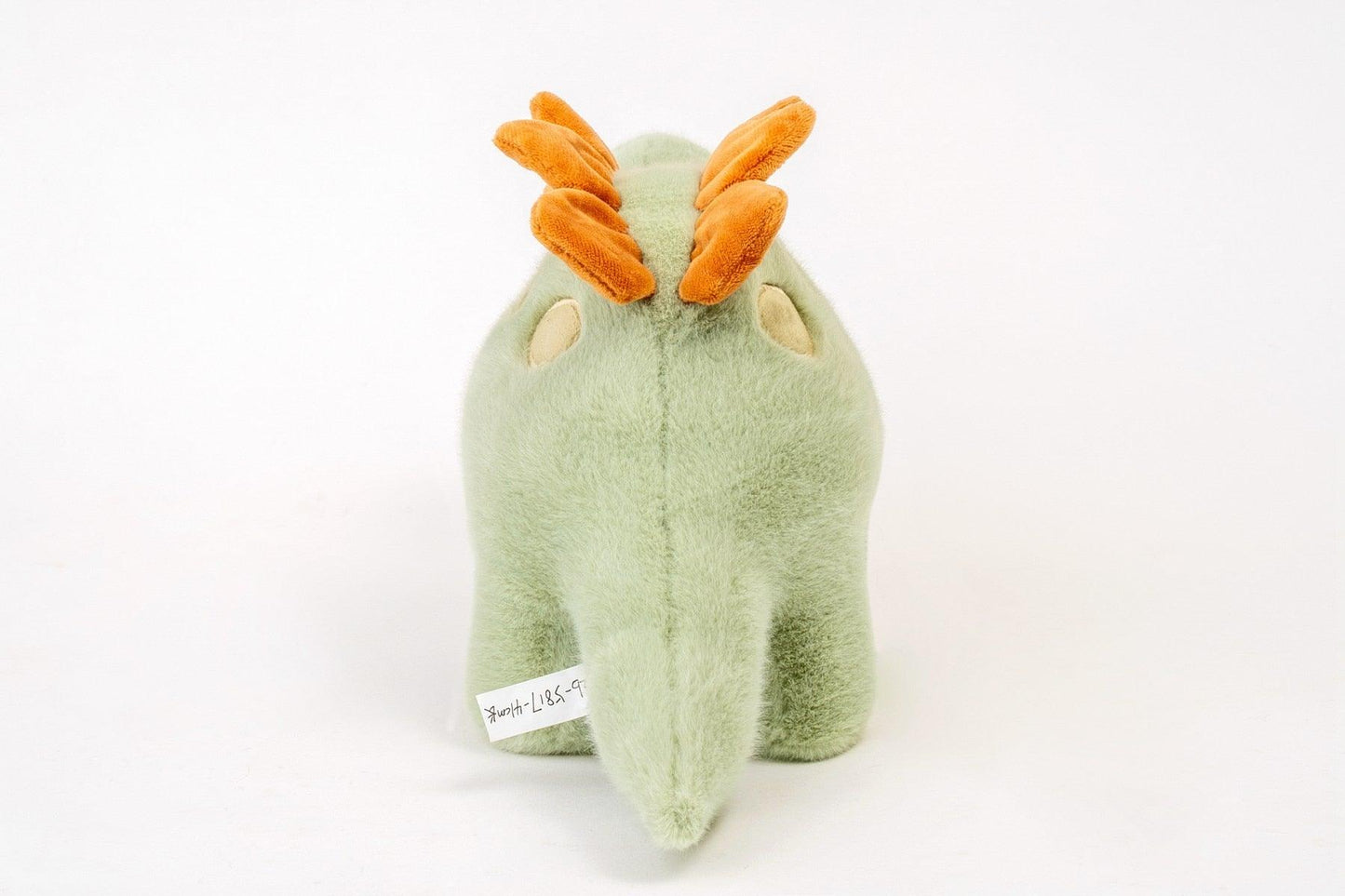 Dinosaure en peluche vert posé sur un fond neutre