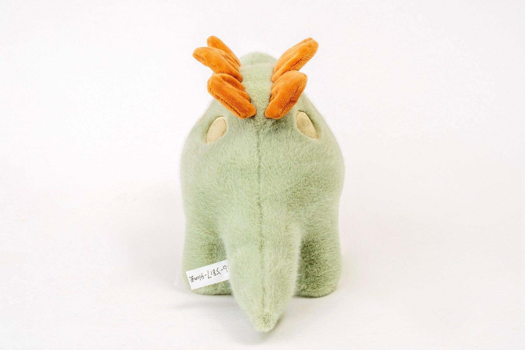 Dinosaure en peluche vert posé sur un fond neutre