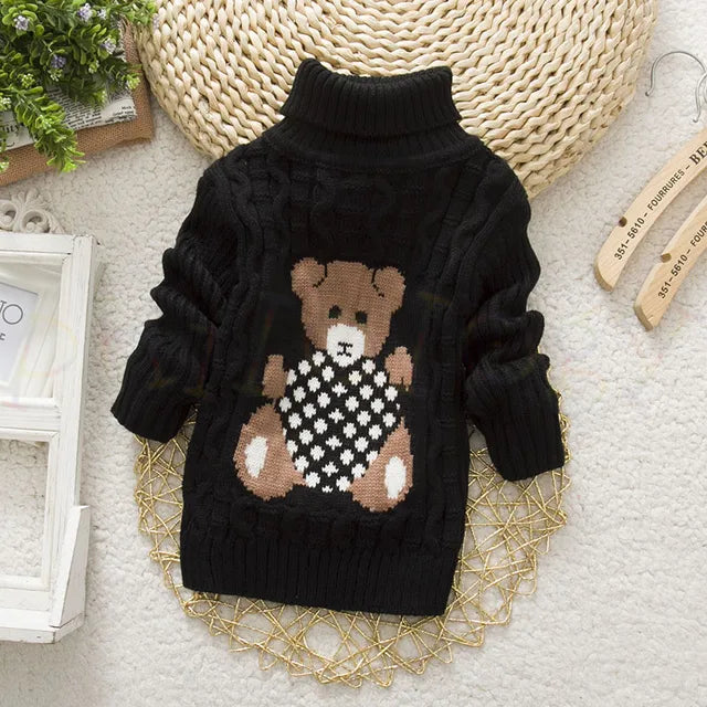 Enfant assis, vêtu d'un pull en fibres acryliques épaisses