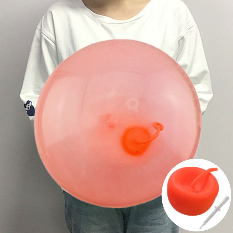 Enfants poussant une balle gonflable sur la pelouse