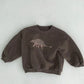 Gros plan sur le motif dinosaure amusant du sweat enfant