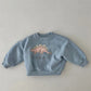 Enfant portant un sweat vert avec motif dinosaure