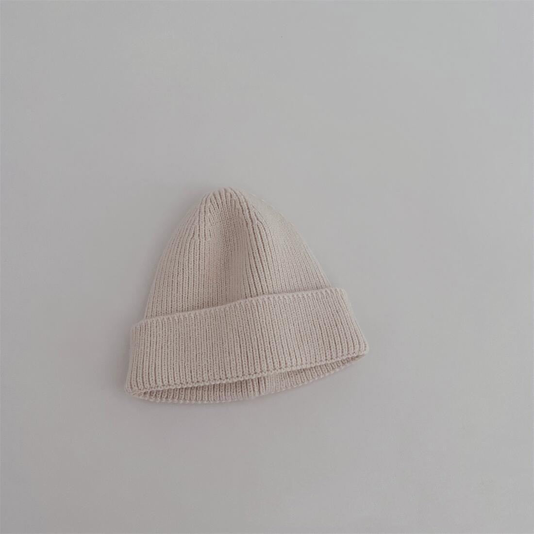 Bonnet lilas en coton, posé sur un tissu coloré