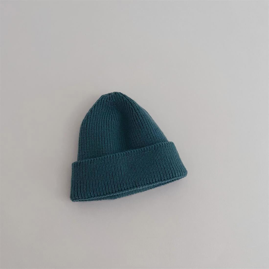 Bonnet beige en coton, plié sur un fond neutre