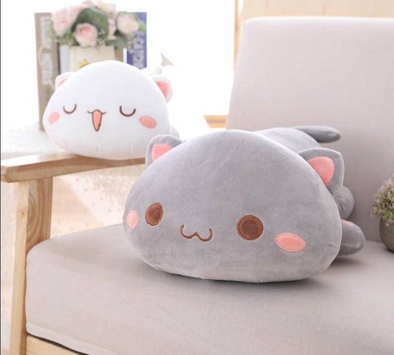Chat en peluche kawaii allongé sur un lit blanc