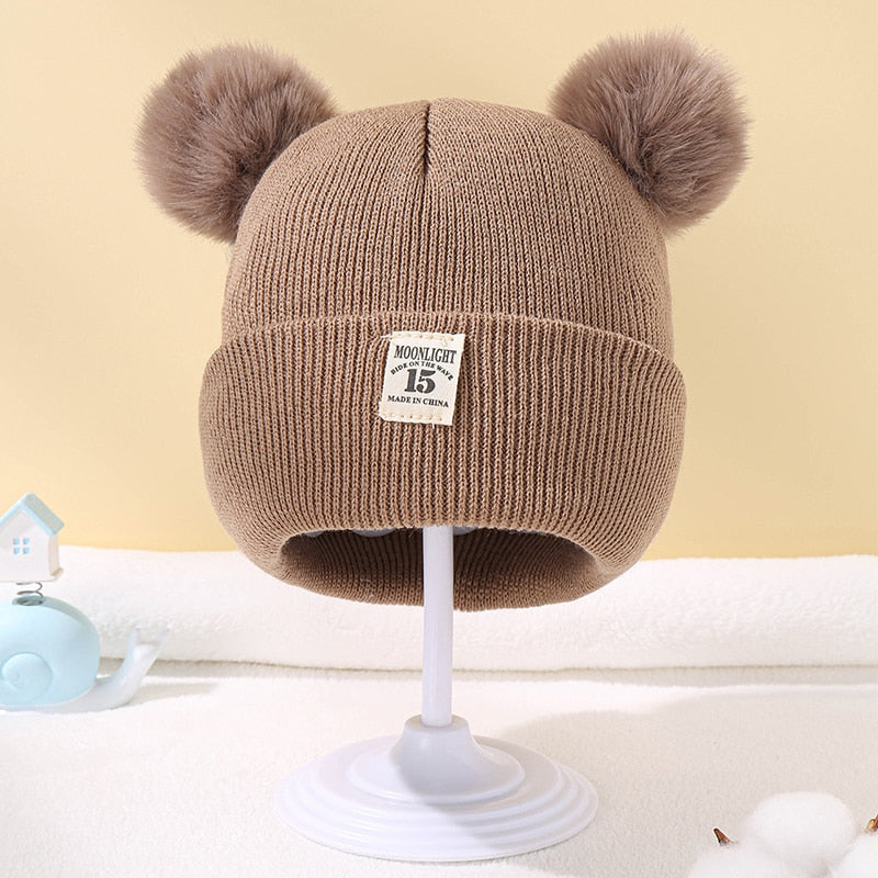 Bonnet enfant en laine avec pompon sur fond uni