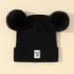 Bonnet enfant en tricot avec pompon sur table en bois