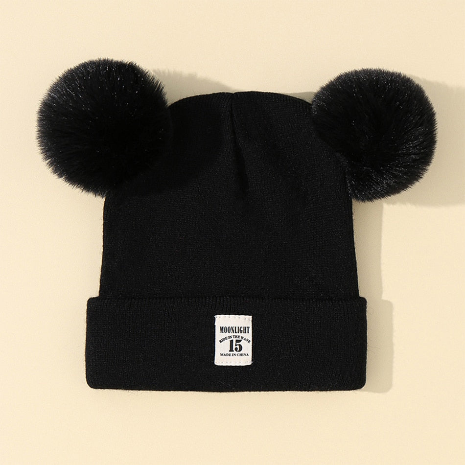 Bonnet enfant en tricot avec pompon sur table en bois