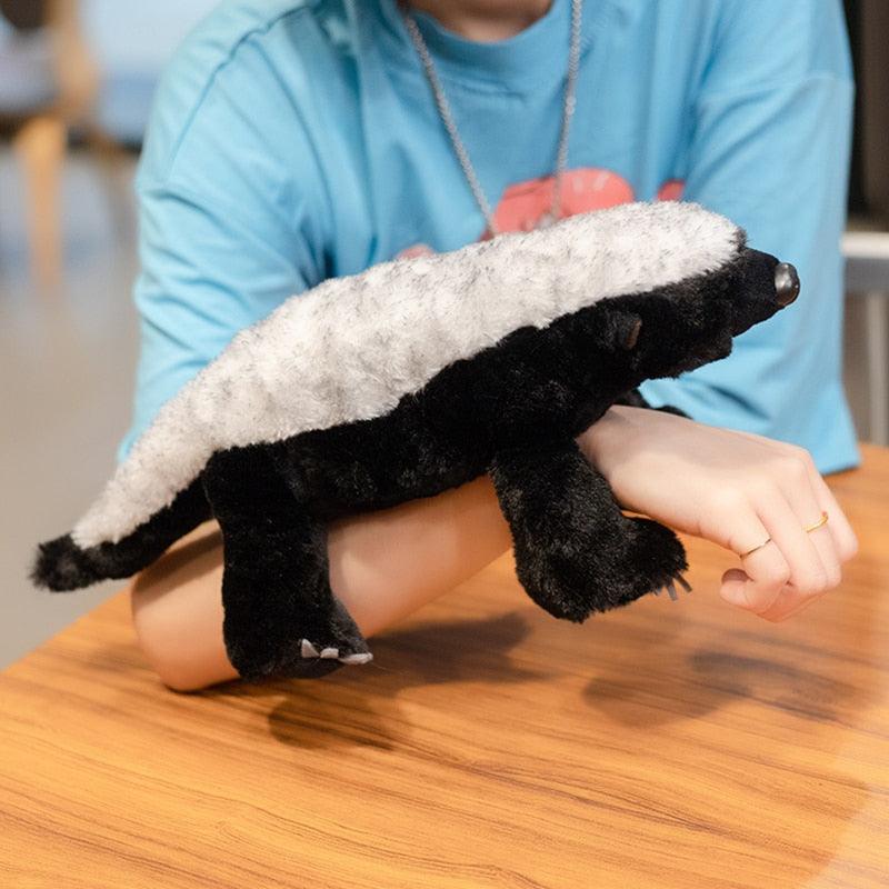 Peluche blaireau en position assise sur une surface douce