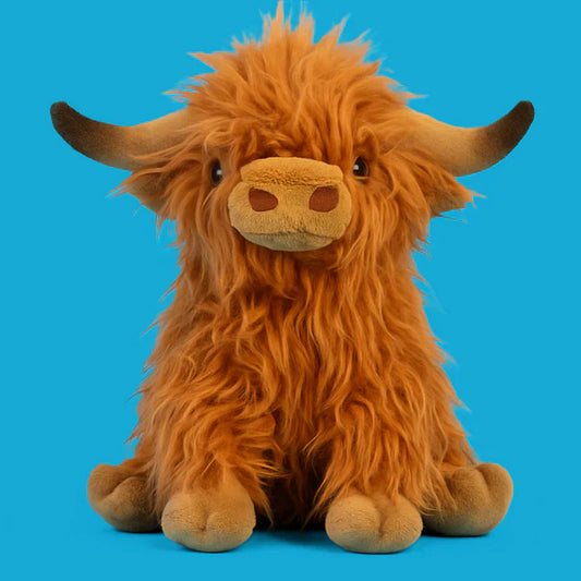 Peluche vache Highlands posée sur une surface en bois
