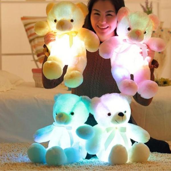 Teddy lumineux posé sur un lit, éclairé doucement