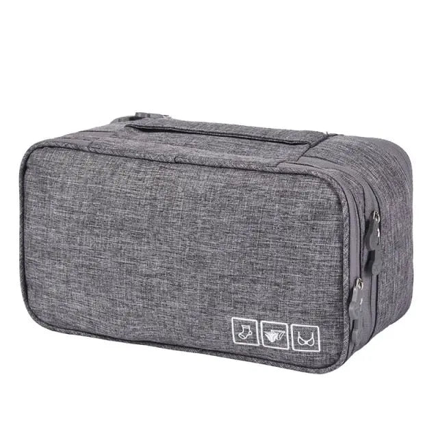 Pochette de voyage grise posée sur une surface blanche