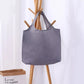 Sac de voyage gris, plié et compact, sur une surface blanche