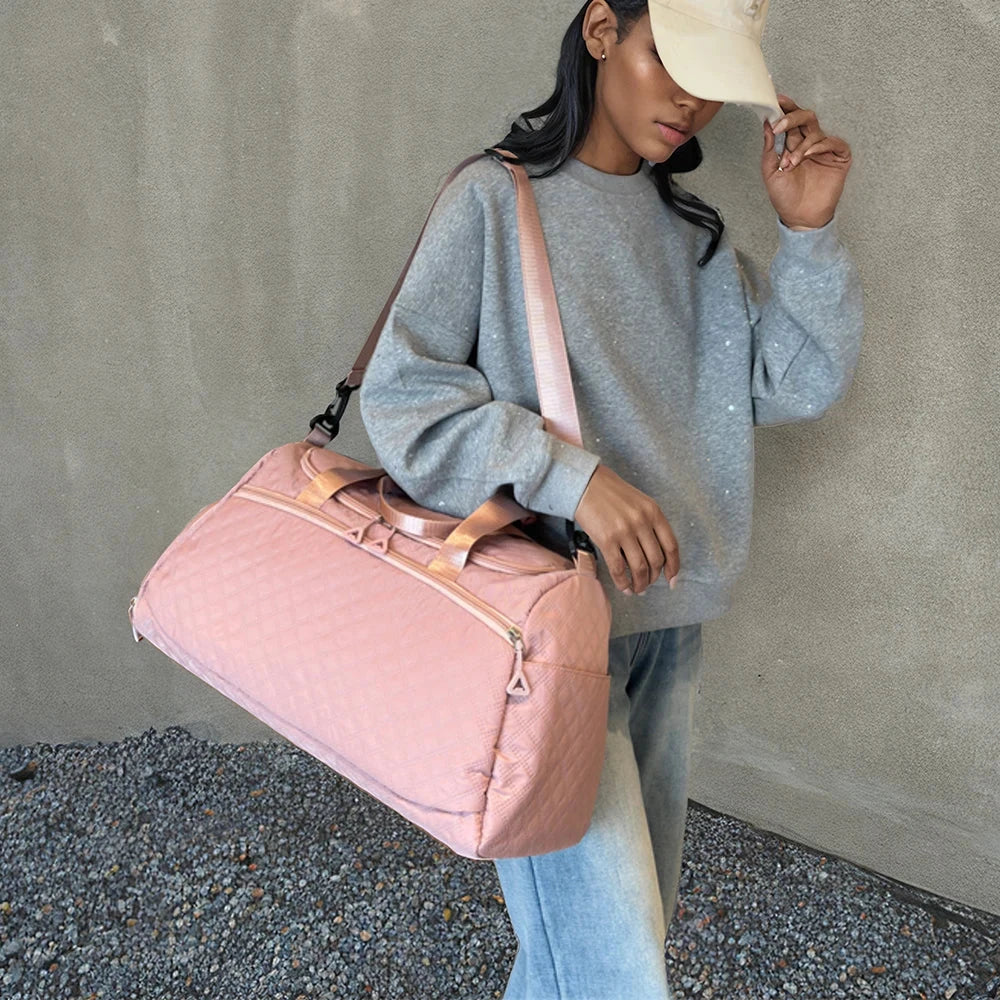 Sac polochon posé sur une valise, sangle visible