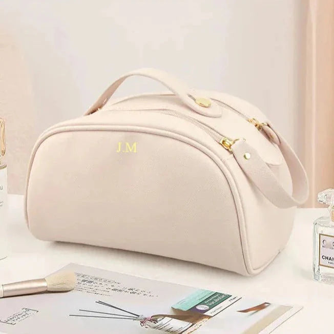Trousse de toilette beige avec initiales dorées visibles